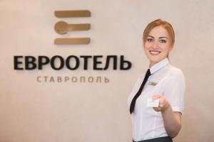 Eine Frau mit weißem Hemd und Krawatte mit Karte. in der Unterkunft Eurootel Stavropol in Stawropol