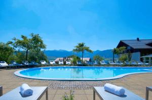 a large swimming pool with chairs and mountains in the background at Allgäu Sonne in Oberstaufen