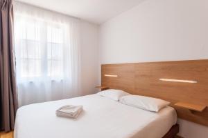 um quarto com uma cama branca e uma cabeceira em madeira em Residhotel Vieux Port em Marselha