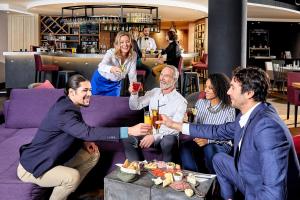 um grupo de pessoas sentadas num sofá roxo com bebidas em Campanile Nice Aéroport em Nice