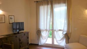カンニジョネにあるAppartamenti La Suaraのリビングルーム(白いカーテン付きの大きな窓付)