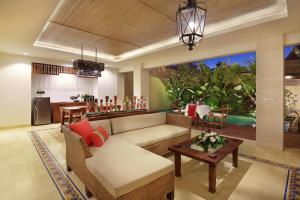 uma sala de estar com um sofá e uma mesa em Kamajaya Villas em Ubud