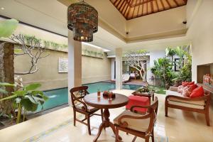a living room with a table and chairs and a pool at Kamajaya Villas in Ubud