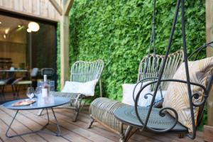 patio z krzesłami i stołami oraz zieloną ścianą w obiekcie T Boutique Hotel w Arcachon