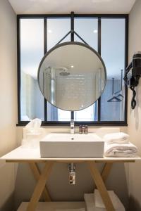 a bathroom with a sink and a large mirror at T Boutique Hotel in Arcachon