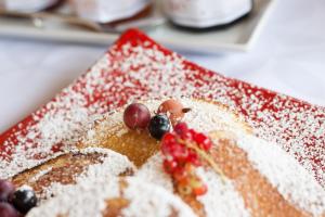 a cake with powdered sugar and berries on a red plate at Chambres d'hôtes Domaine de Nazère in Avezan