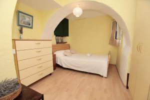 a bedroom with an archway with a bed and a dresser at Phaedra Apartment in Trogir