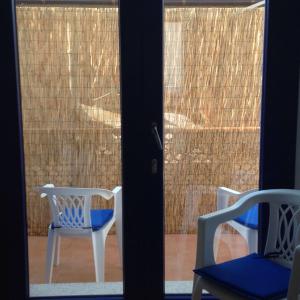 um par de cadeiras sentadas em frente a uma porta de vidro em La Casa Blanca y Azul em SantʼAntìoco