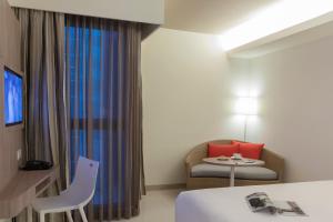 a hotel room with a bed and a chair and a window at Travelodge Pattaya in Pattaya