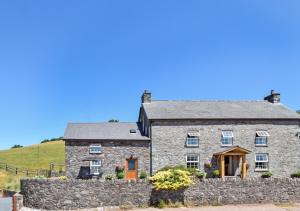 an old stone house with a stone wall at Bwthyn Blaencar in Sennybridge
