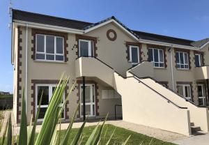 a house with stairs in front of it at Kilkee Holiday Homes (GF - Sleeps 5) in Kilkee