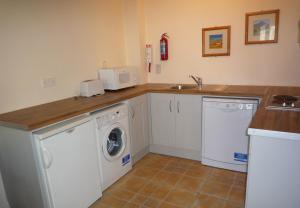 uma cozinha com uma máquina de lavar roupa e um lavatório em Kilkee Holiday Homes (GF - Sleeps 5) em Kilkee