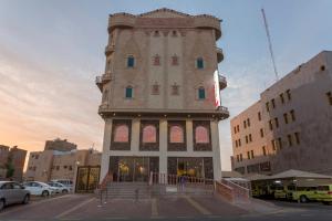 een hoog gebouw op een parkeerplaats met auto's bij Hotel Ritaj Alsahel in Yanbu