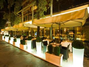 ein Restaurant mit Tischen, Stühlen und Sonnenschirmen in der Nacht in der Unterkunft Hotel Savoy in Pesaro