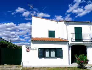 a white house with green shutters and a fence at Casa Rural San Blas in Sanjuanejo +9 photos