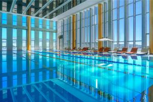 a swimming pool with chairs in a building at Hotels & Preference Hualing Tbilisi in Tbilisi City