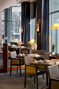 a dining room with tables and chairs and windows at Hotel Savigny Frankfurt City in Frankfurt