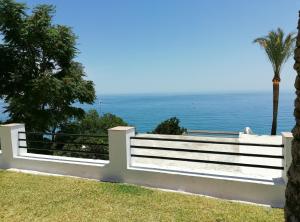 een wit hek met de oceaan op de achtergrond bij Apartamentos La Roca Rentals in Torremolinos