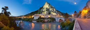 uma montanha ao lado de um rio com uma ponte em L'Oustalet em Sisteron