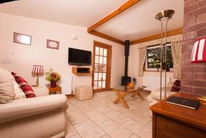 a living room with a couch and a tv at Greyfield Farm Cottages in Farmborough