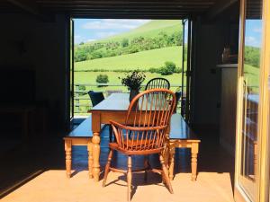 uma mesa de madeira e cadeiras num alpendre com uma janela em The House In The Hills em Velindre
