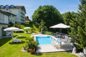 un cortile con piscina, sedie e ombrelloni di Haus Panorama a Drobollach am Faakersee