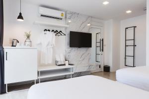 ein weißes Schlafzimmer mit Bett und Fernseher in der Unterkunft Zivi Nimman in Chiang Mai