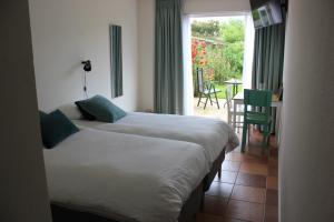 a bedroom with two beds and a table and a window at Bluesheep-texel in De Koog