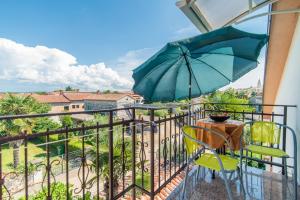 a balcony with a table and an umbrella at Apartment Vilma Funtana in Funtana