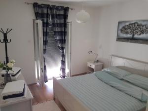 una camera bianca con un letto e una finestra di Holiday Home Begonja a Privlaka (Brevilacqua)