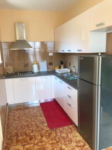 eine Küche mit weißen Schränken und einem Kühlschrank aus Edelstahl in der Unterkunft Alloggio da Massimo in San Leonardo