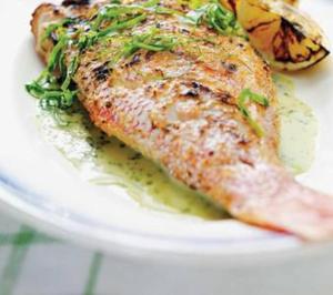 un piatto bianco con un pezzo di pesce con i fiori di Chambre d'hôte Kay Arlette - chez l'habitant a Le Robert