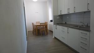 Apartment MDK Sokolov في سوكولوف: مطبخ مع دواليب بيضاء وطاولة وكراسي