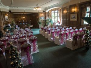 une chambre pleine de chaises et d'arbres de Noël dans l'établissement Petwood Hotel, à Woodhall Spa