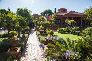 una casa con un jardín con árboles y flores en Ivory Manor Boutique Hotel, en Pretoria