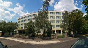 ブダペストにあるホテル ナップの目の前に木々が植えられた白い大きな建物