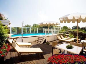 eine Terrasse mit Stühlen, Tischen und einem Pool in der Unterkunft Hotel Savoy in Pesaro