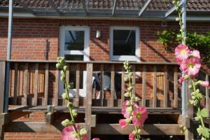 a house with a wooden deck with pink flowers at Ferienwohnung im Kieler Süden in Kiel