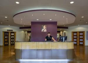 a woman sitting at a counter in a lobby at East Sussex National Hotel, Golf Resort & Spa in Uckfield