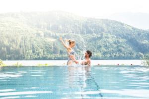 a man and woman in the water in a lake at Villa Postillion am See in Millstatt