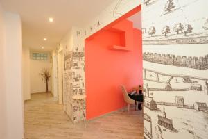 a hallway with an orange wall with drawings on it at B&B Ariston Pisa Tower in Pisa