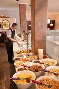 a buffet with many bowls of food and a man in a kitchen at Jennys Huamatl in Serfaus