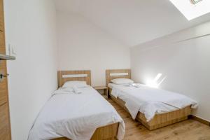 two beds in a room with white walls and wood floors at Apartmani Luka Meljine in Meljine +41 photos