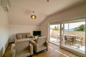 a living room with a table and chairs and a television at Apartmani Luka Meljine in Meljine