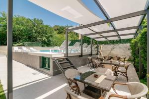 a patio with tables and chairs and a swimming pool at Apartmani Luka Meljine in Meljine