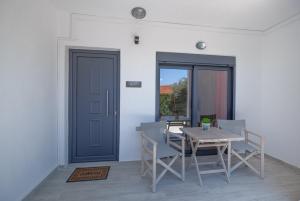 une salle à manger avec une table, des chaises et une porte bleue dans l'établissement Atoli Studios, à Skala Marion