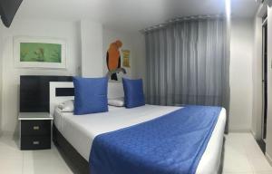 a bedroom with a large bed with blue pillows at Hotel Bahia in Villavicencio
