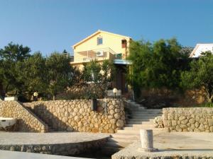 a yellow house with a stone wall and stairs at Apartman JURJEVIĆ in Barić Draga