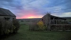 eine alte Scheune auf einem Feld mit Sonnenuntergang im Hintergrund in der Unterkunft Maison d'hôtes La Roulotte des 4 Saisons in Sazeray