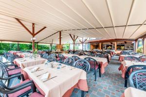 restauracja z białymi stołami i krzesłami oraz stolarką w obiekcie Albergo Ristorante Svizzero w mieście Capolago